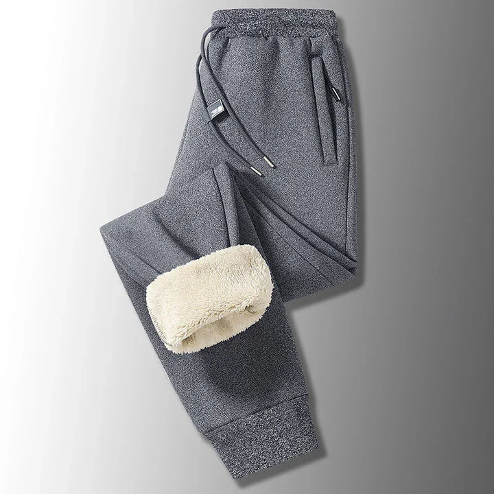 Gray fleece-lined sweatpants with drawstring and side pockets on gradient background
