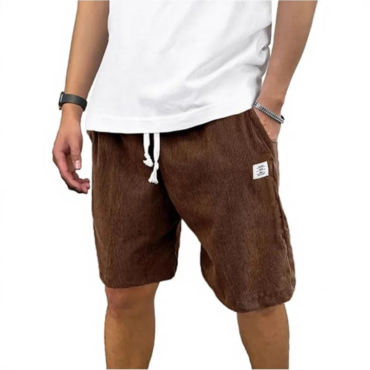 Man wearing brown corduroy shorts with white drawstring and white t-shirt, casual summer outfit
