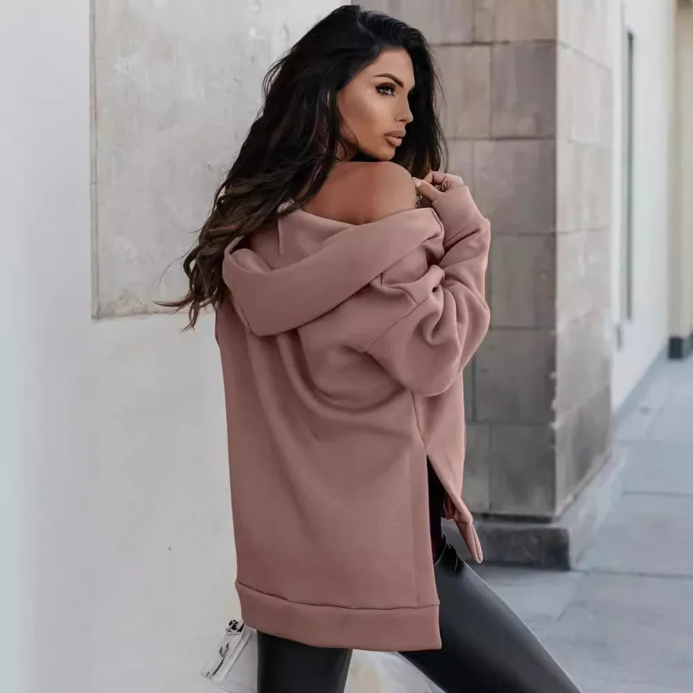 Fashionable woman in oversized mauve hoodie and black leather pants posing on urban street