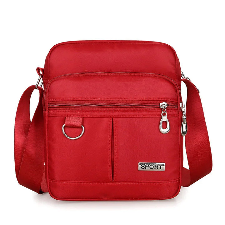 Red sport crossbody bag with adjustable strap, front zip pocket, and metal D-ring detail