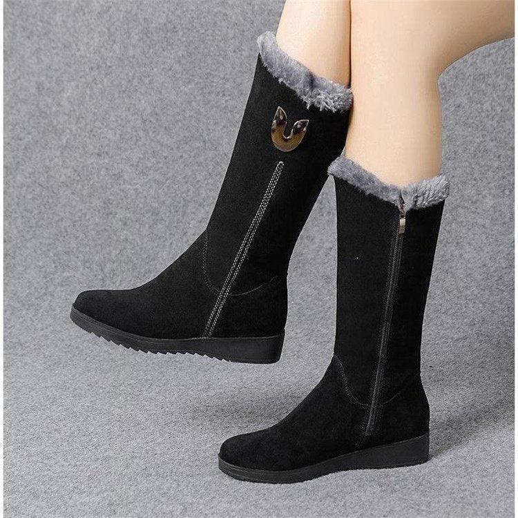 Black mid-calf winter boots with gray fur trim and side zipper on gray background