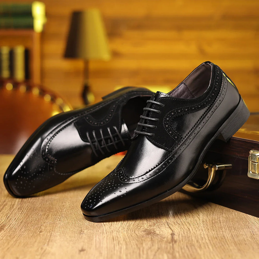 Black polished leather men's brogue dress shoes on wooden surface with blurred lamp background