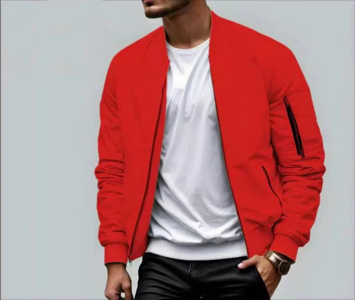 Man wearing bright red bomber jacket over white t-shirt and black pants against gray background