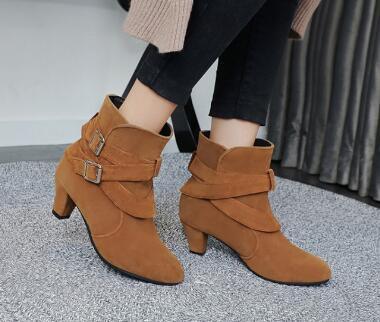 Brown suede ankle boots with double buckle straps and block heels worn with black pants
