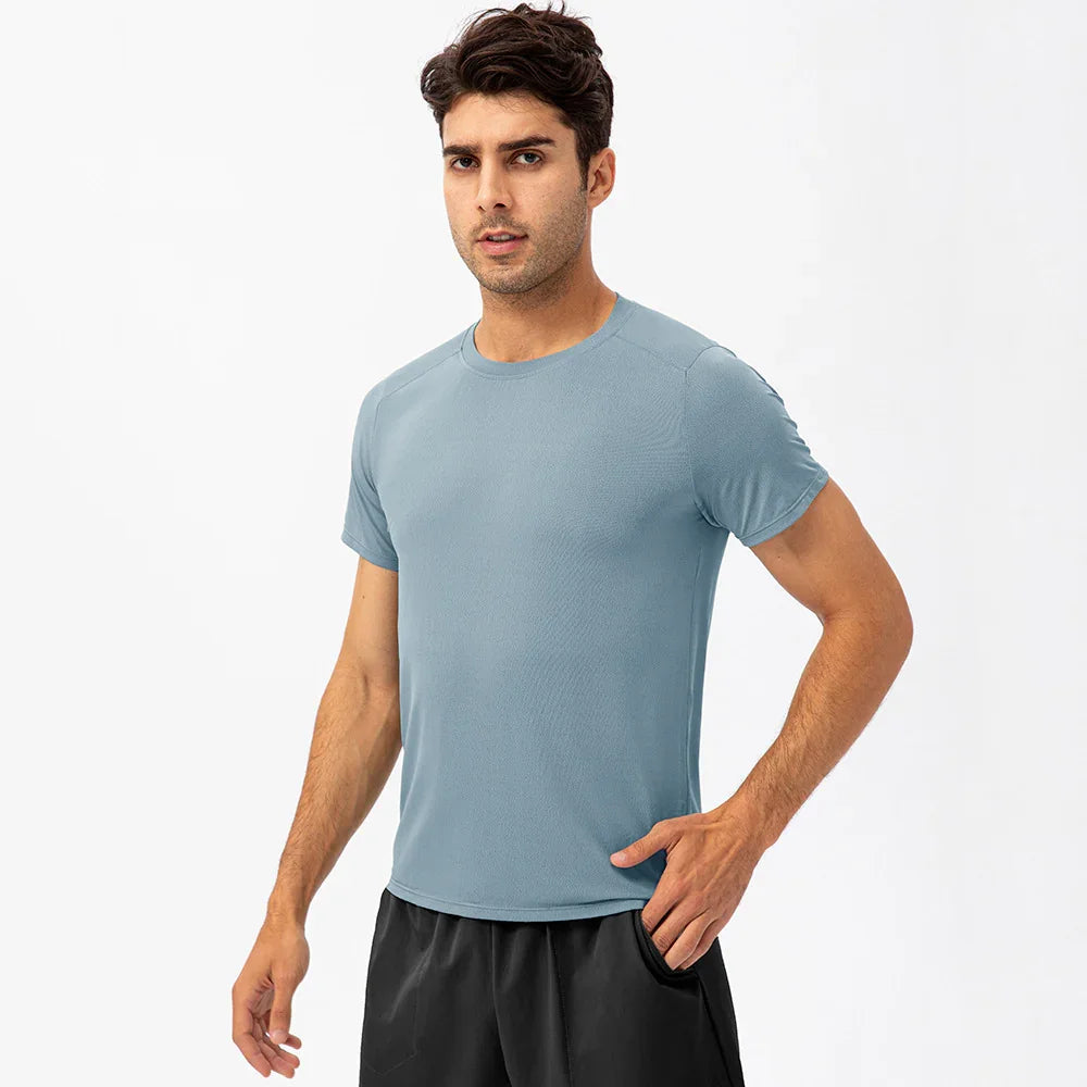 Man wearing light blue athletic t-shirt and black shorts against white background