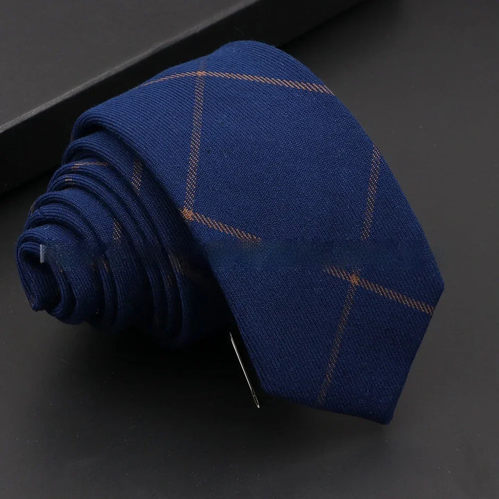 Rolled navy blue necktie with subtle brown windowpane pattern on black surface