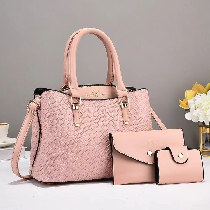 Pink woven leather handbag set with long strap, matching wallet and cardholder on white table