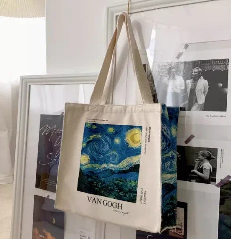 Van Gogh Starry Night canvas tote bag hanging in front of framed art prints