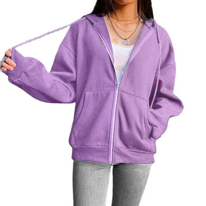 Woman wearing oversized purple zip-up hoodie with front pockets and chain necklaces