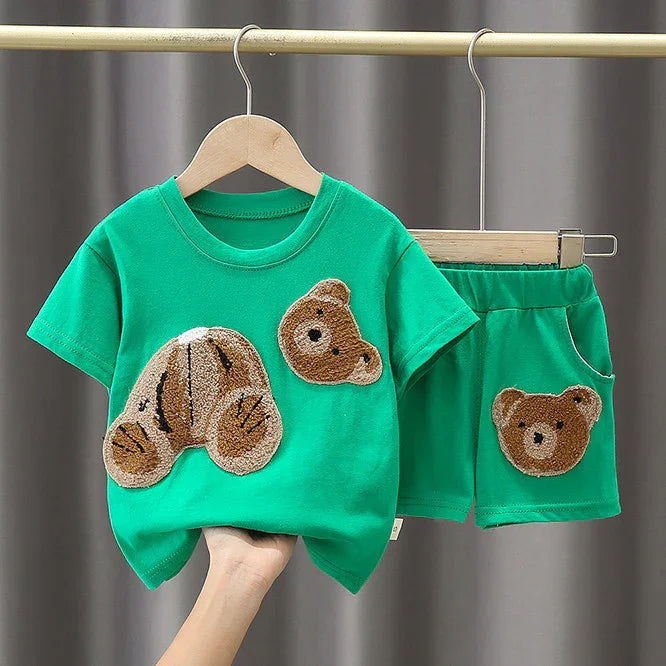 Green toddler outfit with cute teddy bear appliques on t-shirt and shorts, hanging on wooden hangers