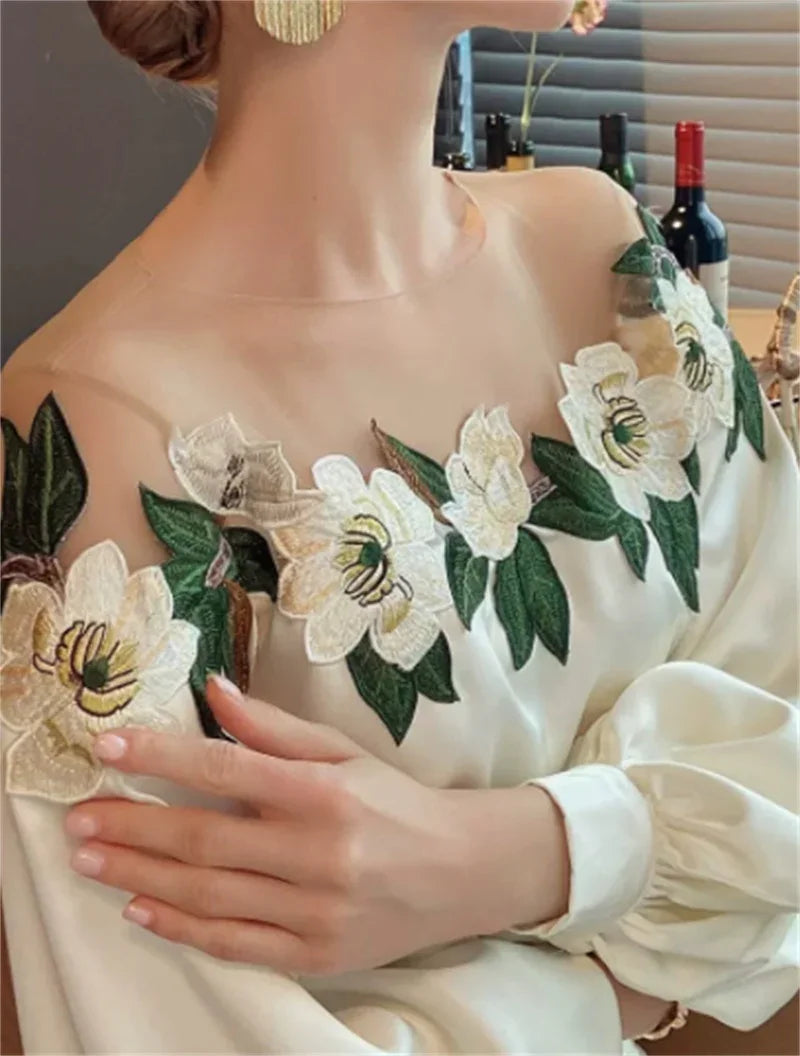 Woman wearing white off-shoulder blouse with green and white floral embroidery and gold earrings