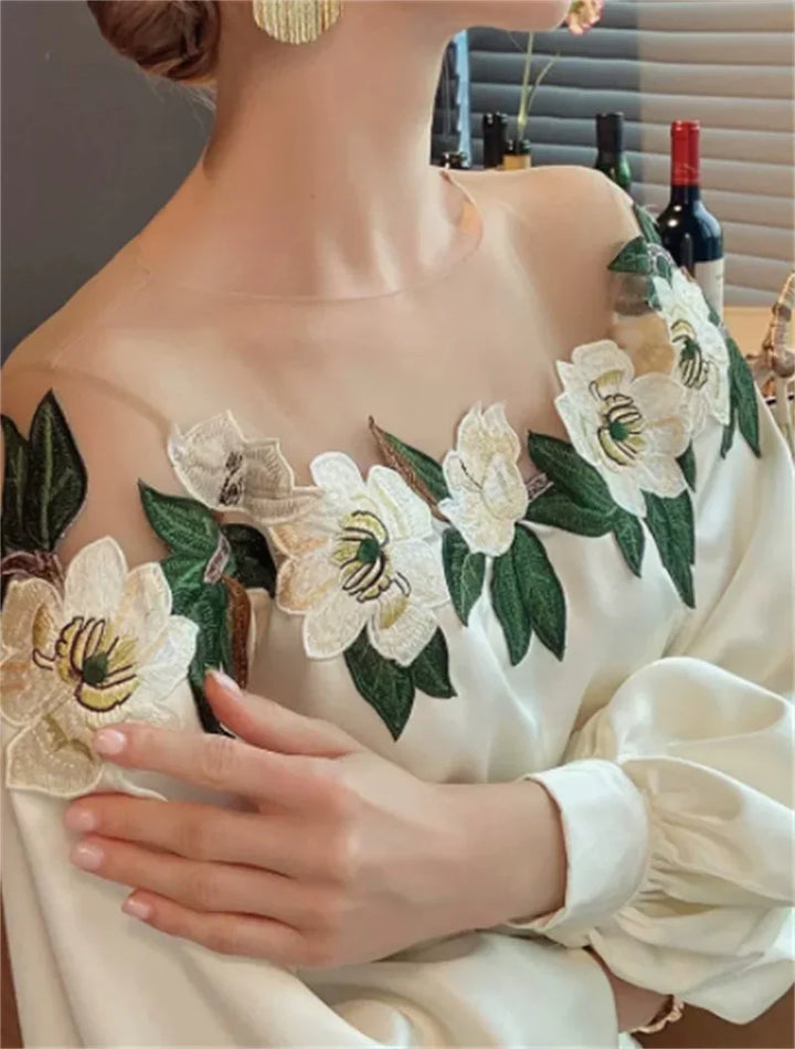 Woman wearing white off-shoulder blouse with green and white floral embroidery and gold earrings