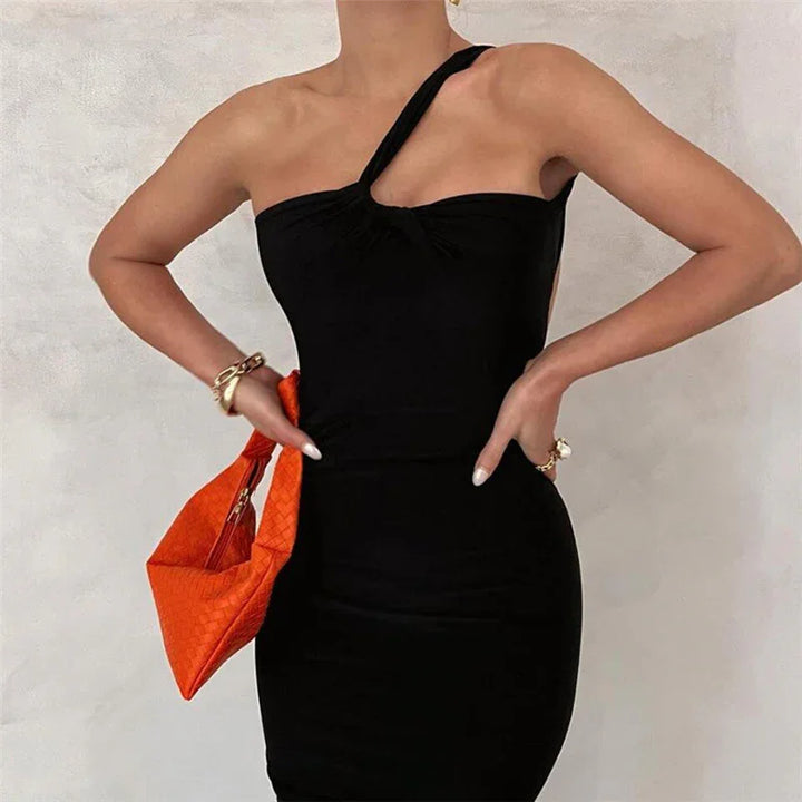 Woman wearing one-shoulder black dress with orange woven handbag and gold accessories
