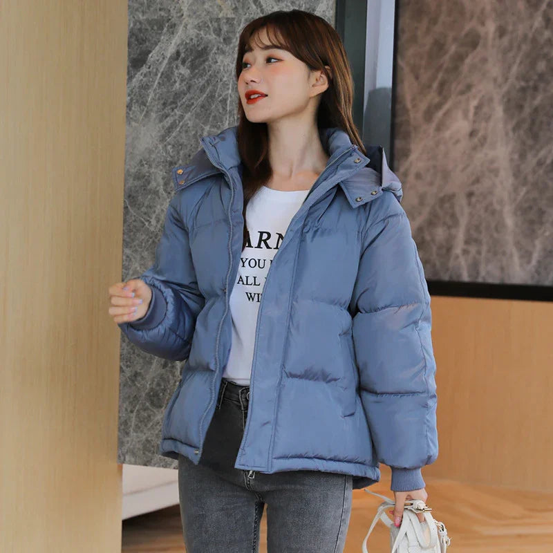 Woman wearing blue puffer jacket and white graphic t-shirt standing indoors with stylish casual outfit