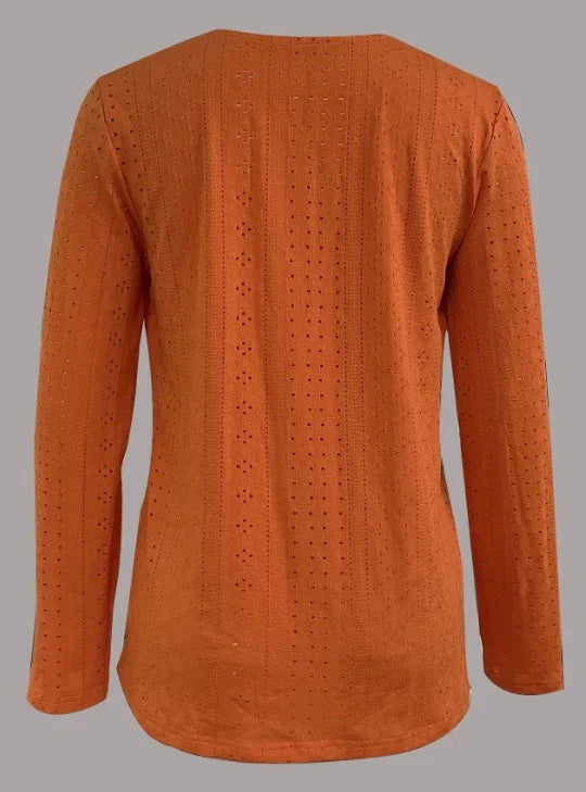 Back view of long-sleeve burnt orange knit top with perforated pattern on gray background