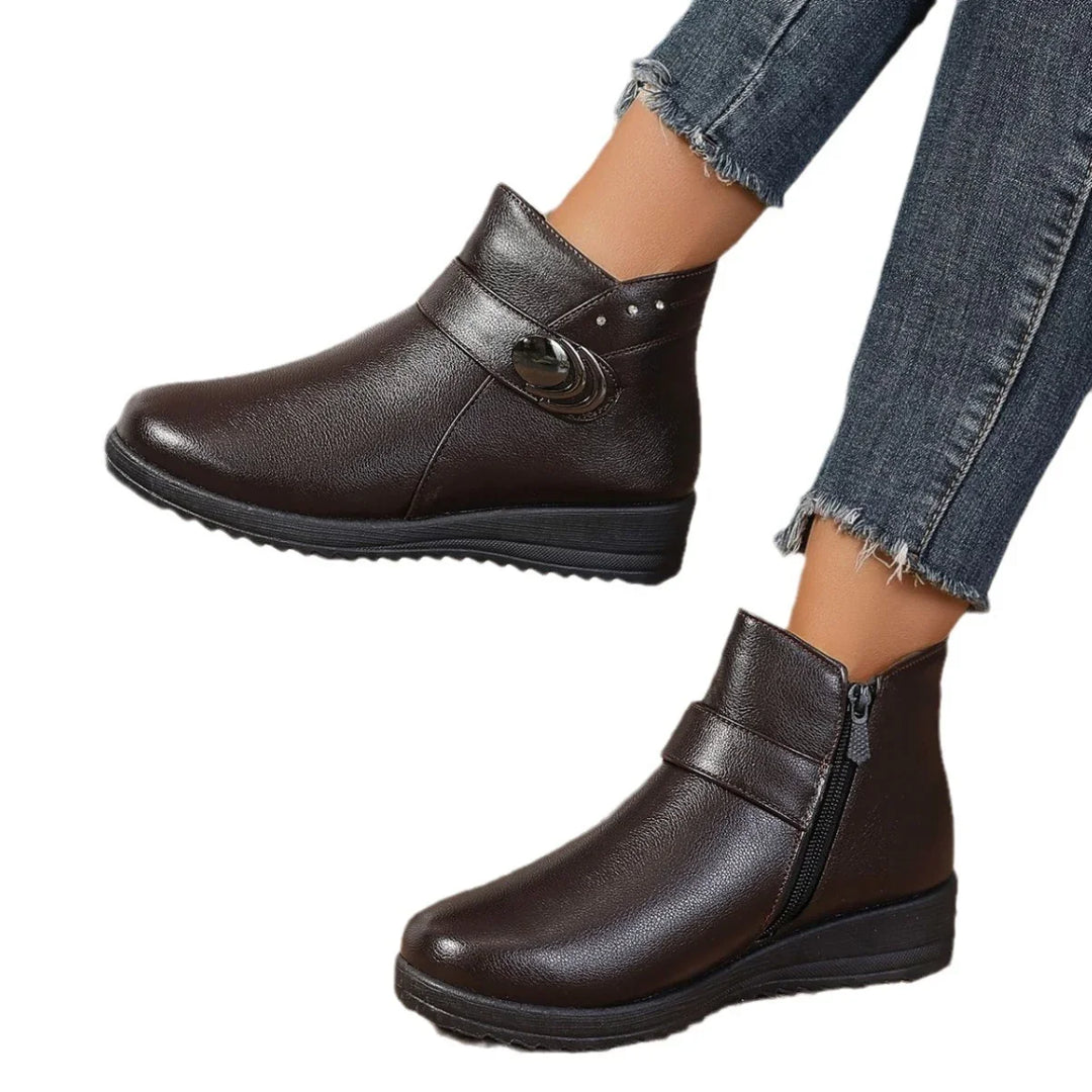 Brown leather ankle boots with decorative button and side zipper worn with frayed hem jeans