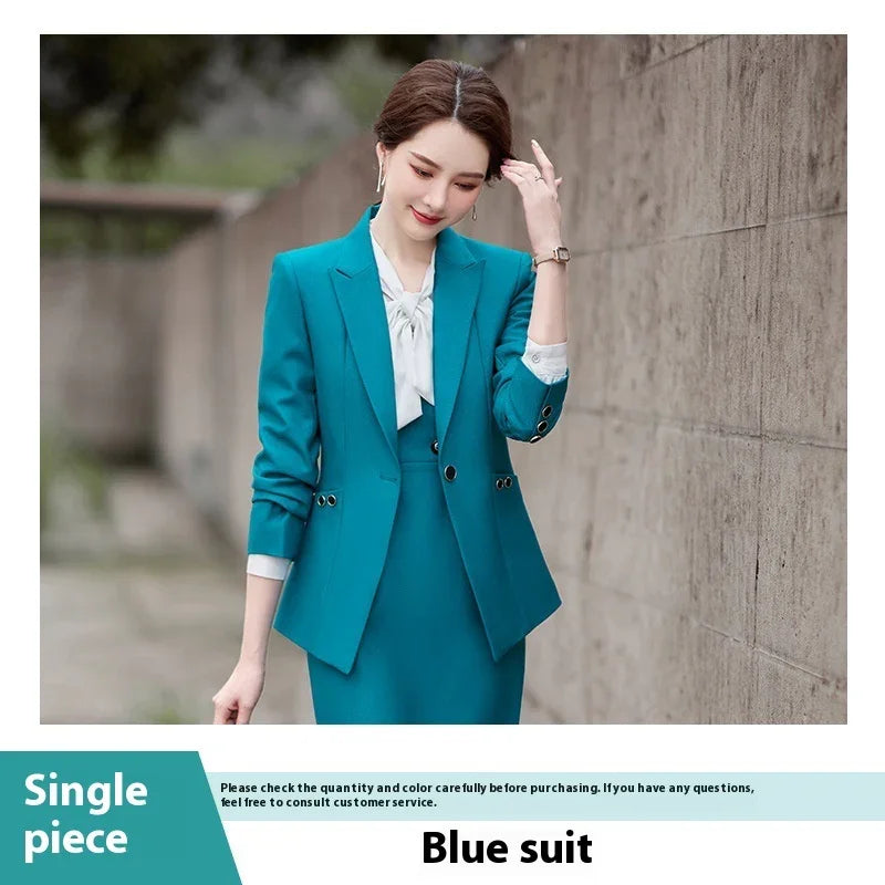 Elegant woman wearing a teal blue business suit with a white blouse, standing by a concrete wall