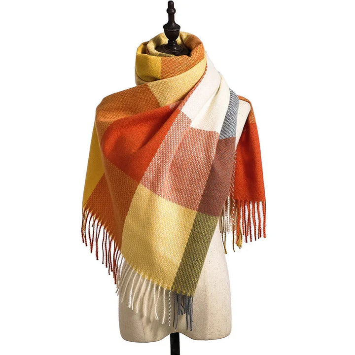Multicolored plaid wool scarf with fringe edges on mannequin, featuring orange, yellow, white, and brown blocks