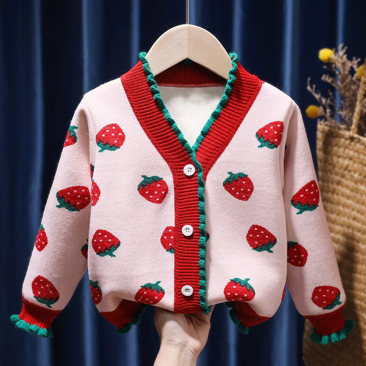 Pink toddler cardigan with red strawberry patterns, red neckline and buttons, green ruffle trim