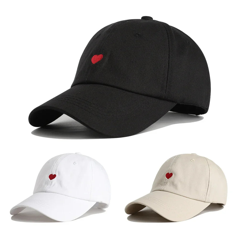 Black, white, and beige baseball caps with small red heart embroidery on front