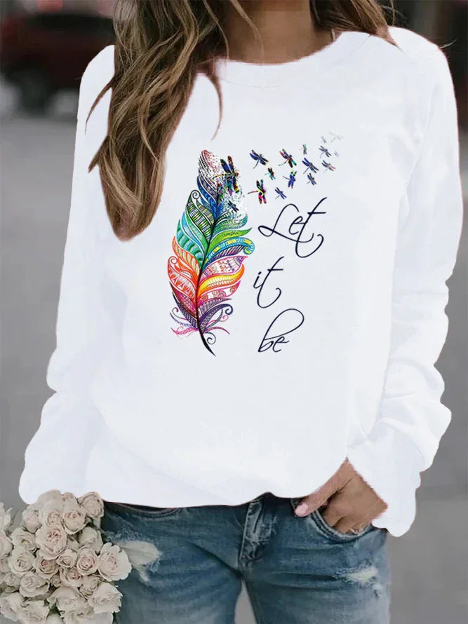 White sweatshirt with colorful feather and dragonflies design, text 'Let it be', worn with blue jeans
