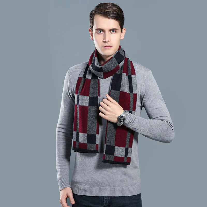 Man wearing a gray sweater and plaid scarf in red, black, and gray against gray background