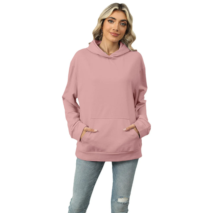 Woman wearing a dusty pink oversized hoodie with front pocket and light blue ripped jeans