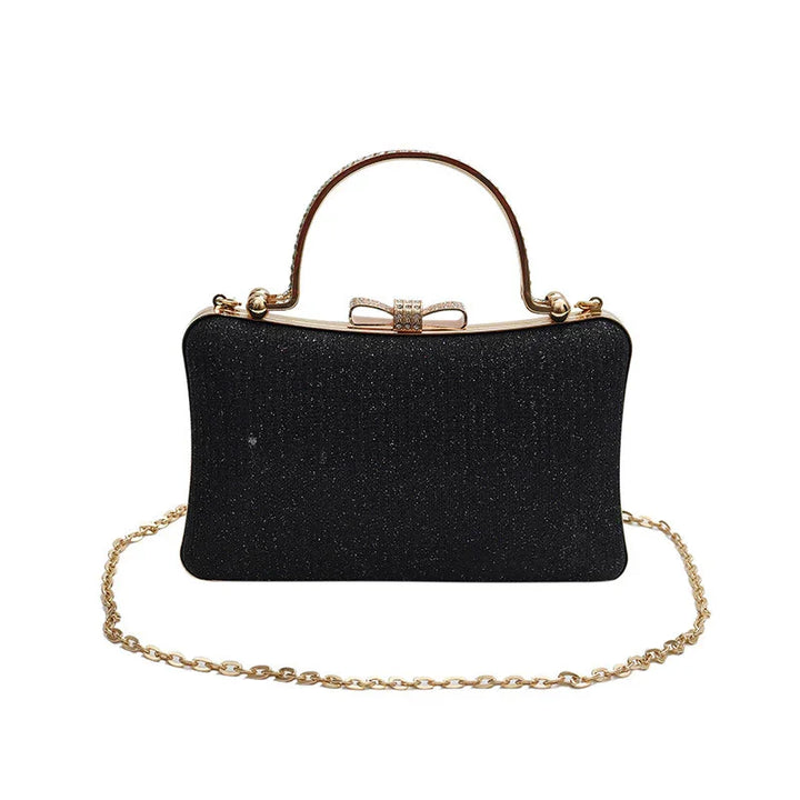 Black glitter evening clutch handbag with gold bow clasp, top handle, and gold chain strap