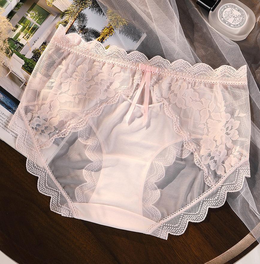 Delicate pink lace women’s underwear with floral patterns, placed on a wooden surface with magazine and white net fabric