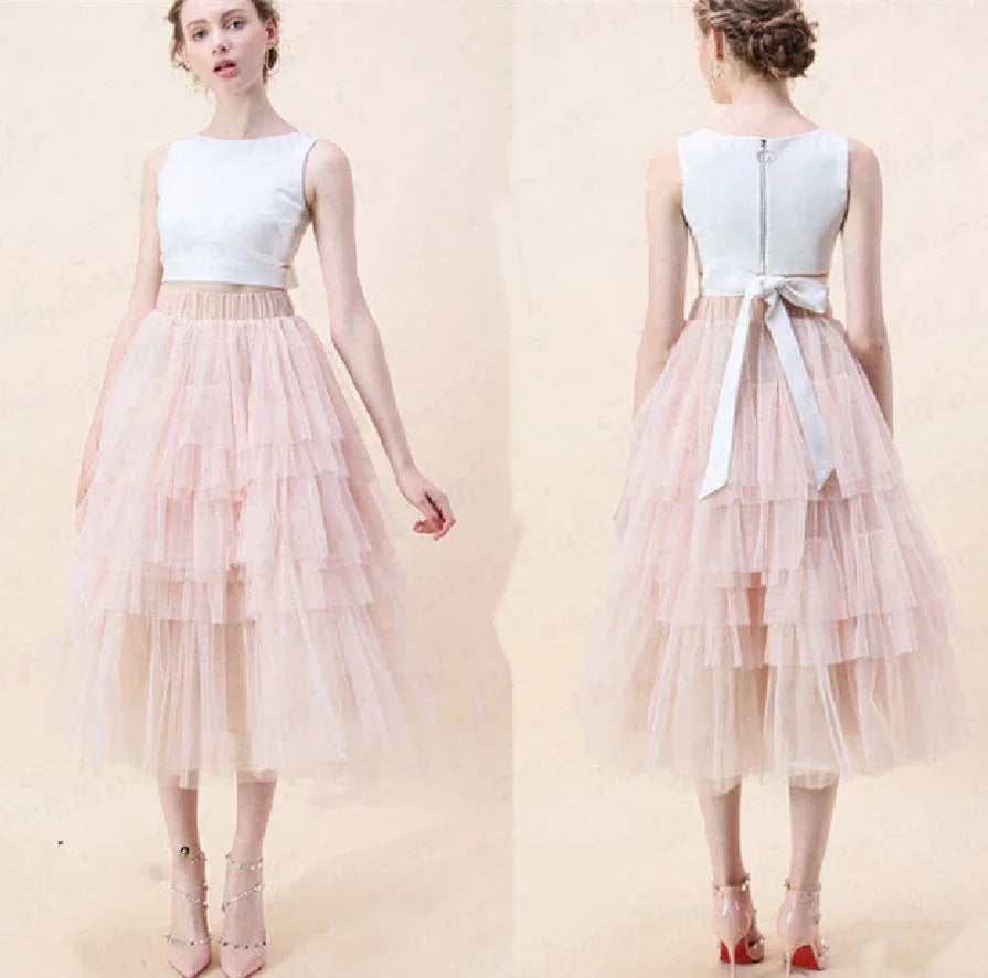 Woman wearing sleeveless white crop top and layered blush pink tulle midi skirt, front and back views