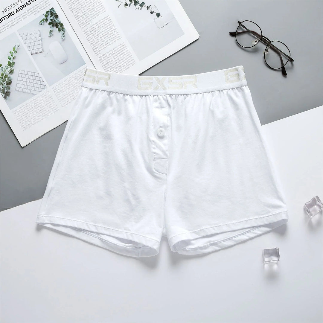 White men's boxer shorts with GXSR waistband on white and gray background with glasses and open magazine