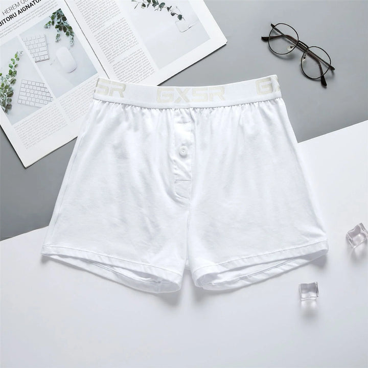 White men's boxer shorts with GXSR waistband on white and gray background with glasses and open magazine