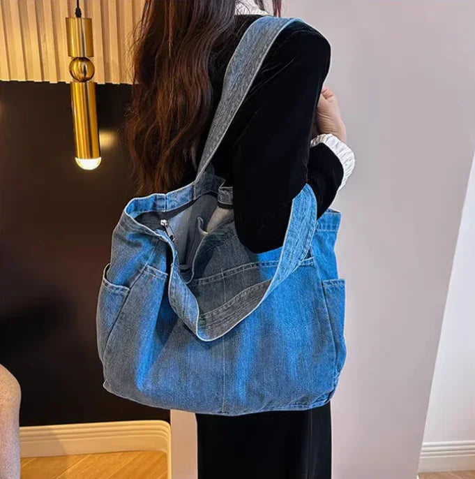 Woman wearing black holding large blue denim tote bag with pockets in modern interior