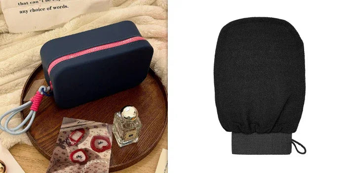 Black travel toiletry bag with pink zipper on wooden tray beside perfume bottle and printed fabric