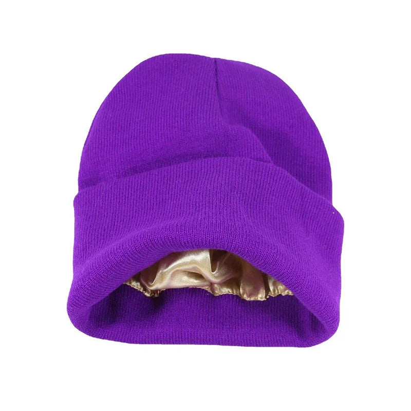 Purple knit beanie hat with golden satin lining inside on white background