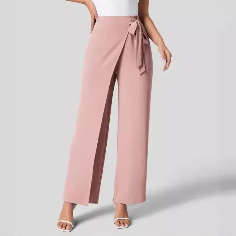 Women’s high-waist pink wrap pants with wide legs and side tie belt, styled with white heels