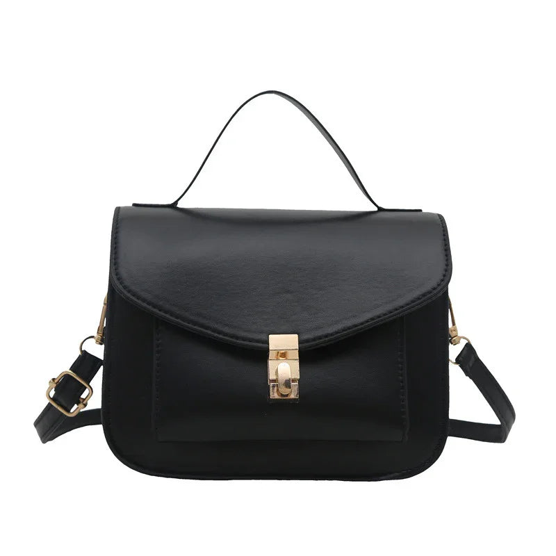 Black leather handbag with top handle and gold clasp closure, featuring adjustable shoulder strap
