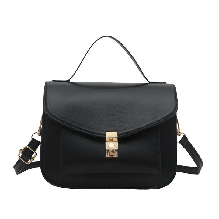 Black leather handbag with top handle and gold clasp closure, featuring adjustable shoulder strap