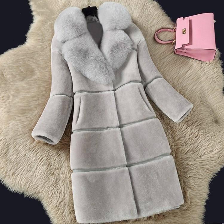 Luxurious light gray shearling coat with plush fur collar displayed on a cream shag rug with a pink handbag nearby