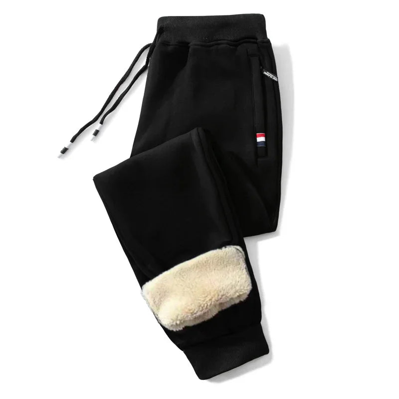 Black fleece-lined jogger pants with drawstring waist and side zipper pockets featuring small red, white, and blue flag detail