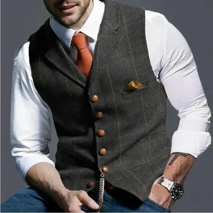 Man wearing gray plaid vest with brown buttons, white shirt, orange tie, and gold pocket square