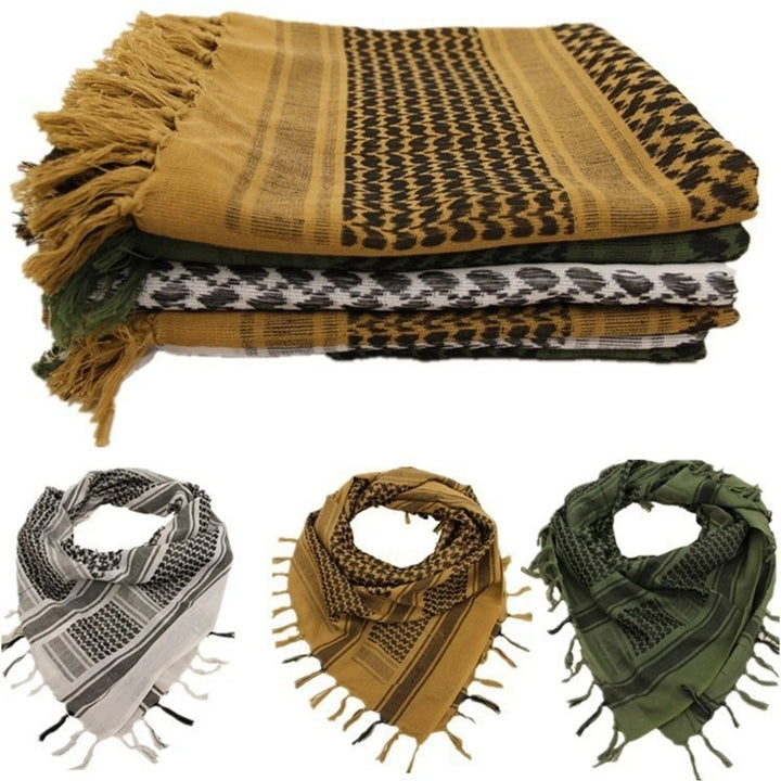 Stack of traditional keffiyeh scarves in tan, white, and green with black patterns and fringed edges