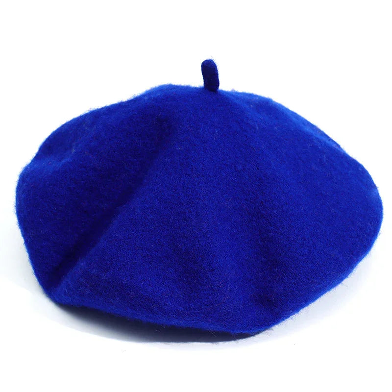Bright royal blue wool beret hat with classic small top stem on white background