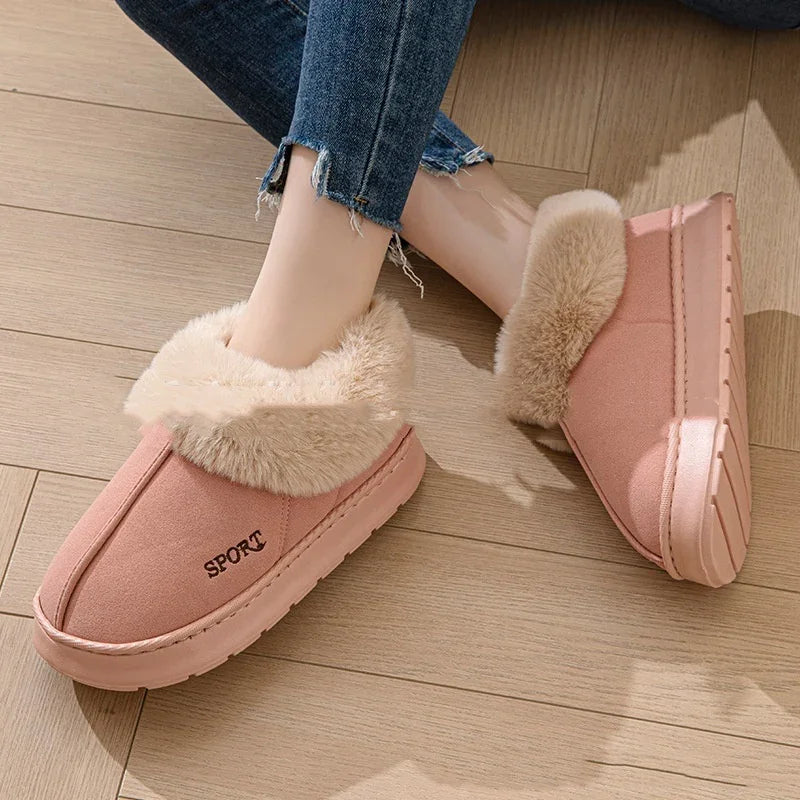 Pink faux fur-lined winter slippers with SPORT text, worn with frayed hem jeans on wooden floor