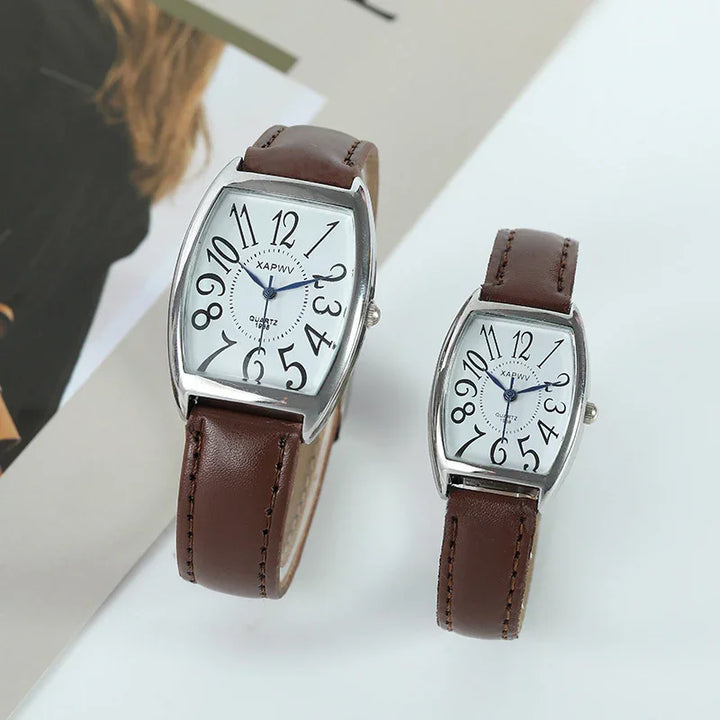 Two wristwatches with white distorted numeral dials and brown leather straps on a white surface