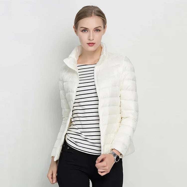 Woman wearing white quilted jacket over black and white striped shirt with black pants on white background