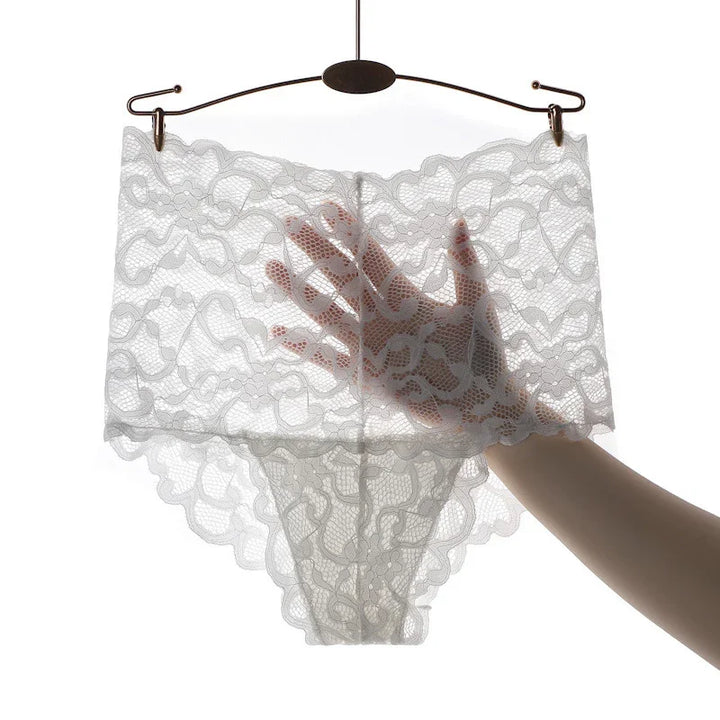 White lace women's underwear held on hanger with hand behind, showing delicate floral pattern