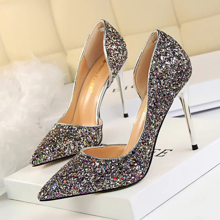 Pair of glittery multicolor high heel stiletto shoes with pointed toes on a white box