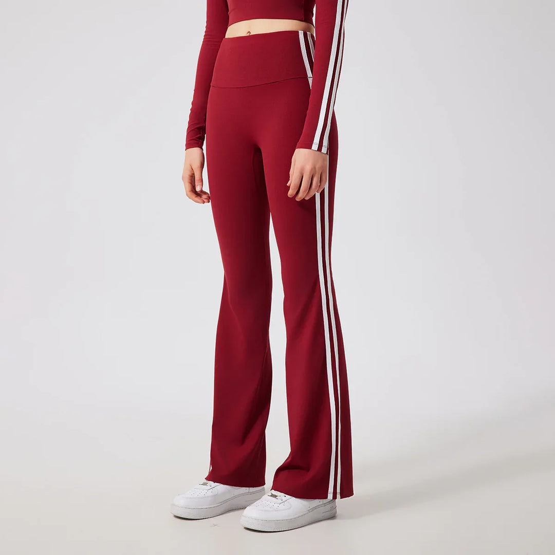 woman wearing maroon flared pants with white side stripes and matching long sleeve crop top with white stripes