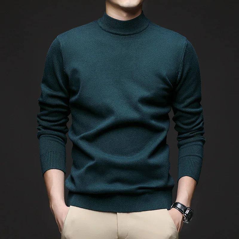 Man wearing dark green turtleneck sweater and beige pants with watch on wrist